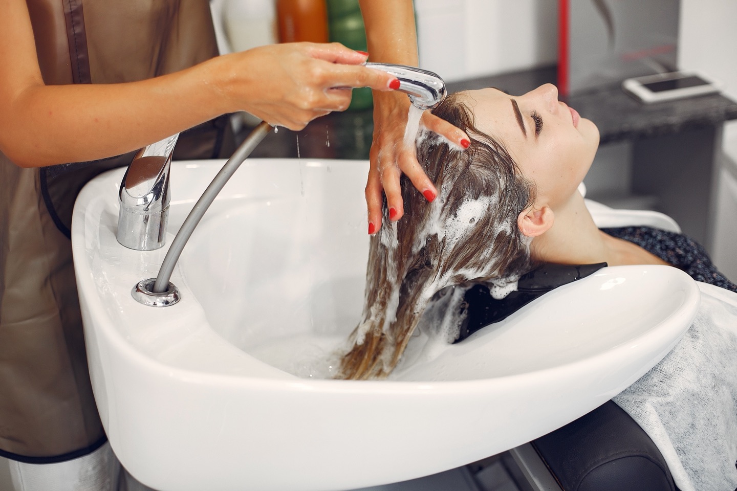 Hairdresser washing her client's hair in the salon basin